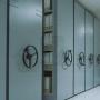 Máximo aprovechamiento del espacio, se consigue compactar las estanterías y aumentar la capacidad de la bodega sin perder el acceso directo a cada estiba. 
Las estanterías se colocan sobre bases móviles guiadas que se desplazan lateralmente; así se suprimen los pasillos y en el momento necesario se abre sólo el de trabajo. Es el operario quien da la orden de apertura de forma manual con timones especiales que se giran suavemente para dicho desplazamiento.
Estas bases disponen de elementos de traslación y diferentes sistemas de seguridad que garantizan un funcionamiento seguro y eficaz.